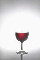 Glas Rotwein auf grauem Hintergrund - TCF002195