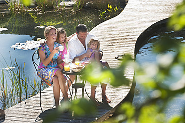 Österreich, Land Salzburg, Familie beim Frühstück auf der Brücke über den Teich - HHF003957