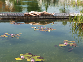 Österreich, Bundesland Salzburg, Junge Frau auf Brücke bei Schwimmbad liegend - HHF003968