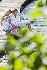 Austria, Salzburg County, Family sitting on bridge over natural pool - HHF003990