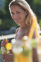 Österreich, Land Salzburg, Junge Frau mit Getränk am Pool - HHF003997