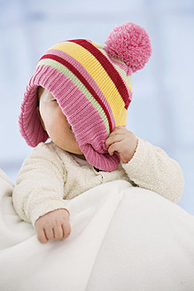 Baby girl covering face with hat, close up - SMOF000518