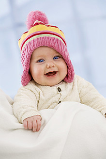 Baby girl in woolly hat, smiling, close up - SMOF000519