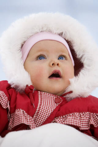 Babymädchen im Schneeanzug mit offenem Mund, lizenzfreies Stockfoto