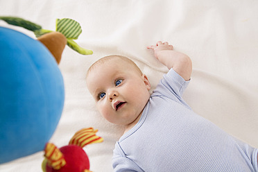 Baby-Mädchen schaut auf Spielzeug, lächelnd - SMOF000527