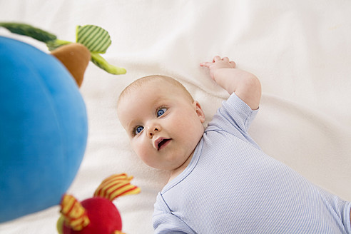 Baby-Mädchen schaut auf Spielzeug, lächelnd - SMOF000527