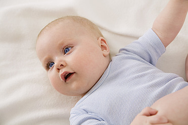 Lächelnd auf einer Babydecke liegendes kleines Mädchen - SMOF000528