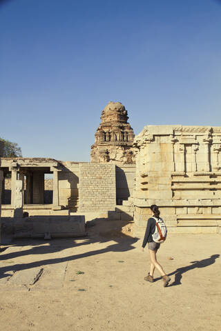 Indien, Karnataka, Hampi, Junge Frau geht auf Tempel zu, lizenzfreies Stockfoto