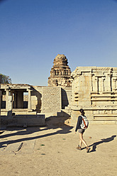 Indien, Karnataka, Hampi, Junge Frau geht auf Tempel zu - MBEF000263