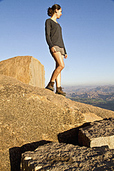 India, Karnataka, Hampi, Young woman walking on rock - MBEF000267