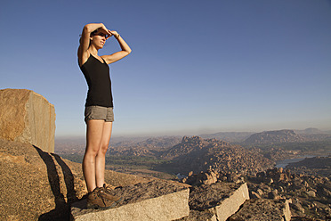 Indien, Karnataka, Hampi, Junge Frau geht auf Felsen - MBEF000269