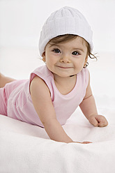 Baby girl lying on baby blanket, smiling - SMOF000504