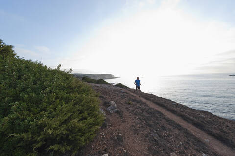 Portugal, Algarve, Älterer Mann joggt an der Küste, lizenzfreies Stockfoto