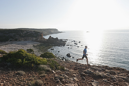 Portugal, Algarve, Älterer Mann joggt an der Küste - MIRF000368