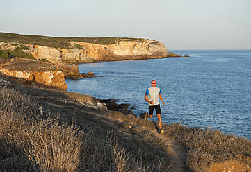 Portugal, Algarve, Älterer Mann joggt an der Küste - MIRF000369
