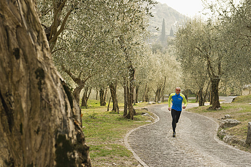 Italien, Älterer Mann joggt auf einem Weg - MIRF000397