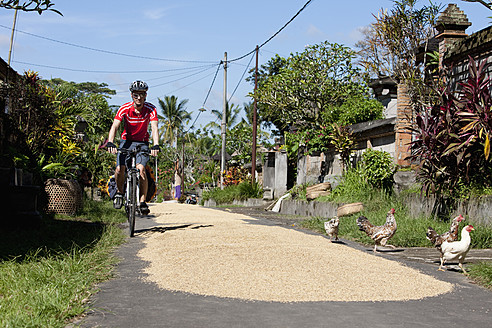 Indonesien, Bali, Tegalalang, Mann radelt durch die Straße - DSF000214