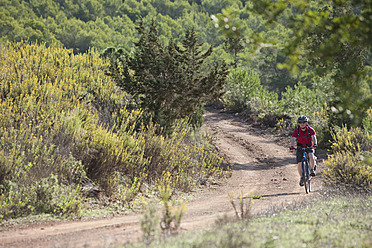 Spanien, Ibiza, Älterer Mann fährt Fahrrad - DSF000310