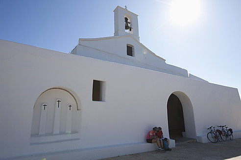 Spanien, Ibiza, Reifer Mann und mittlere erwachsene Frau sitzen vor der Kirche - DSF000312