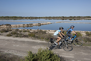 Spain, Formentera, Mature man and mid adult woman riding bicycle - DSF000318