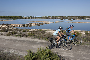 Spanien, Formentera, Älterer Mann und mittlere erwachsene Frau fahren Fahrrad - DSF000318