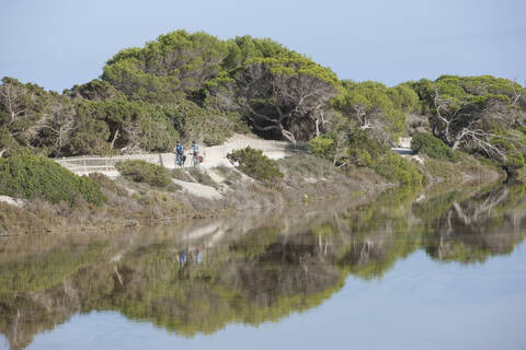 Spanien, Formentera, Älterer Mann und mittlere erwachsene Frau fahren Fahrrad, lizenzfreies Stockfoto