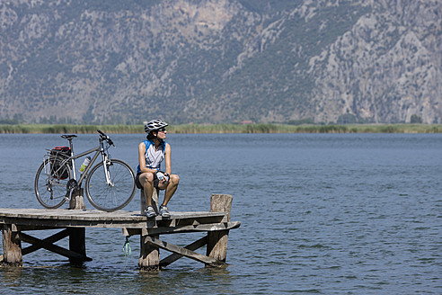 Türkei, Dylan Delta, Mittlere erwachsene Frau auf Steg sitzend mit Fahrrad - DSF000364