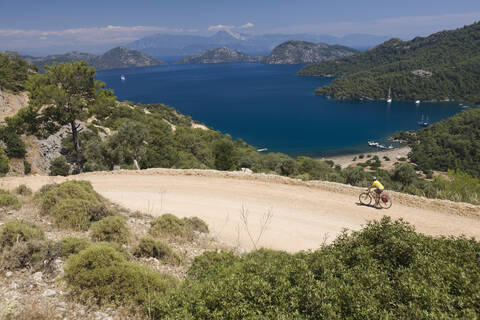 Türkei, Bucht von Sarsala, Mittlere erwachsene Frau fährt Fahrrad, lizenzfreies Stockfoto