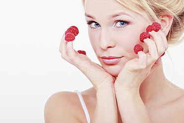 Young woman with raspberries on her fingertips, portrait - WVF000231
