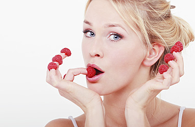 Young woman with raspberries on her fingertips, portrait - WVF000232