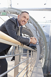 Germany, Leipzig, Businessman leaning on railing, smiling - WESTF018447