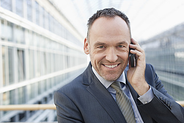 Germany, Leipzig, Businessman on cell phone, smiling, portrait - WESTF018557