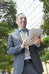 Deutschland, Leipzig, Geschäftsmann mit digitalem Tablet, lächelnd - WESTF018578