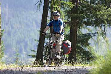 Switzerland, Mature man cycling on dirt track - DSF000397