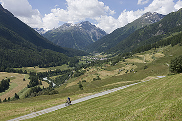 Switzerland, Mature man cycling through country road - DSF000398