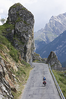 Schweiz, Älterer Mann fährt mit dem Fahrrad durch eine Bergstraße - DSF000401