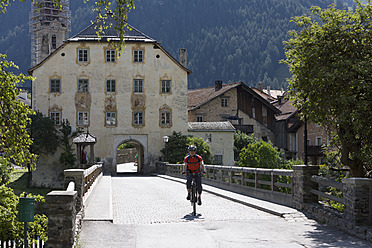 Austria, Mature man cycling on bridge, Pfunds in background - DSF000403