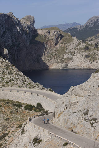 Spanien, Mallorca, Mann und Frau beim Radfahren auf der Straße am Cap de Formento, lizenzfreies Stockfoto