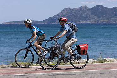 Spanien, Mallorca, Mann und Frau radeln durch die Straße am Meer - DSF000419