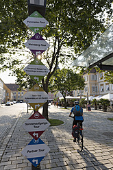 Österreich, Steiermark, Bad Radkersburg, Älterer Mann fährt Fahrrad mit Straßennamenschild - DSF000434