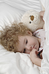Sick girl lying in bed with teddy bear - CRF002143