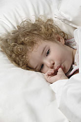 Krankes Mädchen liegt auf dem Bett und lutscht am Daumen - CRF002144