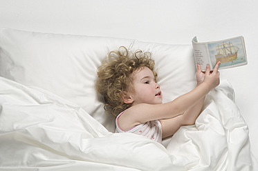 Mädchen liegend auf Bett mit Buch - CRF002160