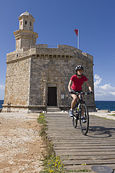 Spain, Menorca, Woman cycling through boardwalk at Ciutadella - DSF000501