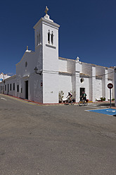 Spanien, Menorca, Mann und Frau radeln an der Kirche in Fornells vorbei - DSF000514
