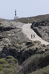 Spanien, Menorca, Mann und Frau beim Radfahren, Cap de Favaritx im Hintergrund - DSF000515