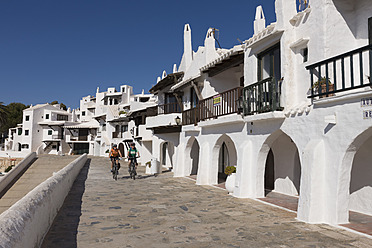 Spanien, Menorca, Binibeca, Mann und Frau radeln über die Promenade - DSF000495
