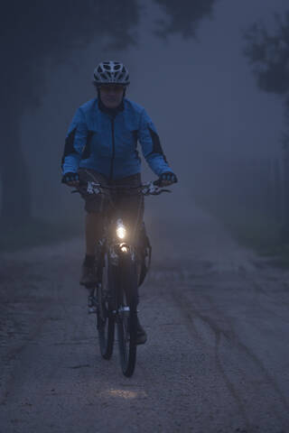 Italien, Toskana, Junge Frau fährt Fahrrad, lizenzfreies Stockfoto