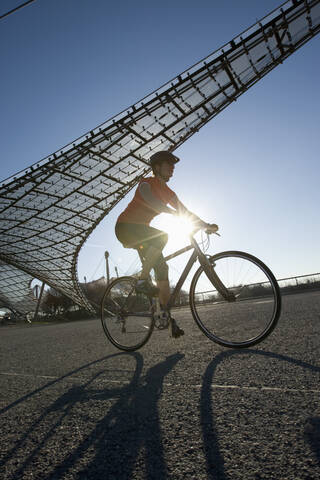 Deutschland, Bayern, München, Mittlere erwachsene Frau fährt Fahrrad, lizenzfreies Stockfoto