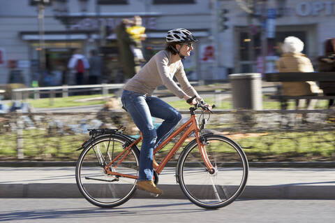 Germany, Bavaria, Munich, Mid adult woman riding bicycle stock photo